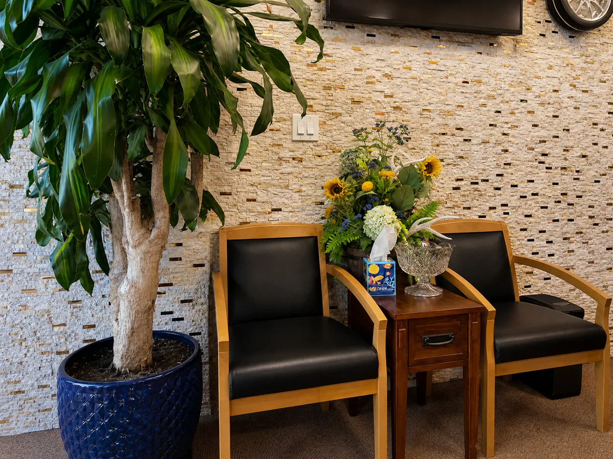 Waiting area with two chairs, sunflowers and a stone mosaic wall